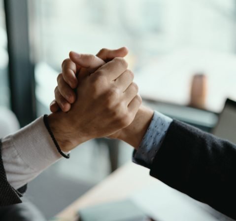 Close up two businessmen shaking hands. Positive management team celebrating victory, successful stock deal, sales growth, won good contract, business achievement and teamwork concept